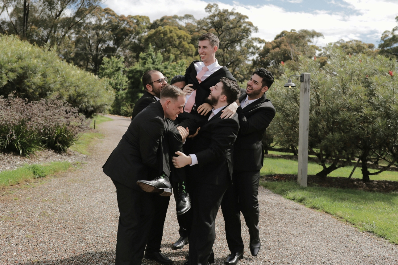 group of men in suits lifting another man in suit