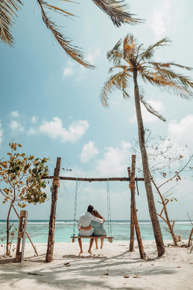 A man and woman sitting on a bench on the beach