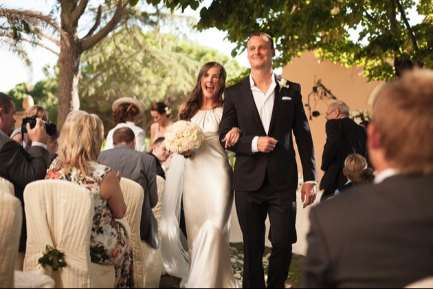 A bride and groom smiling as they walk down the aisle