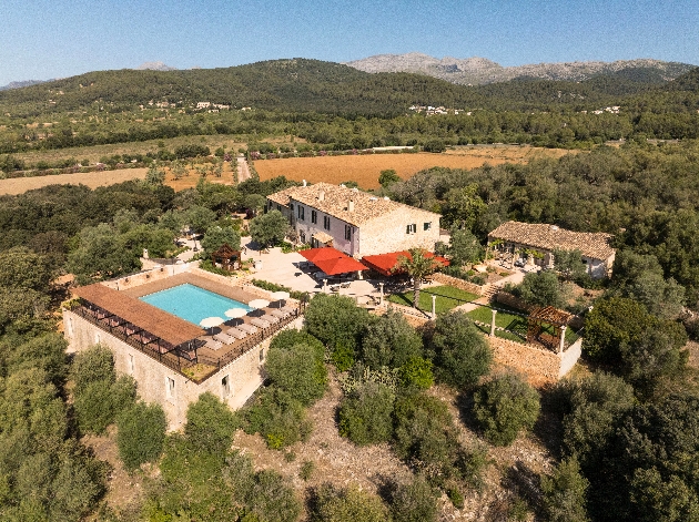 A birdseye view of a villa with a swimming pool surrounded by trees