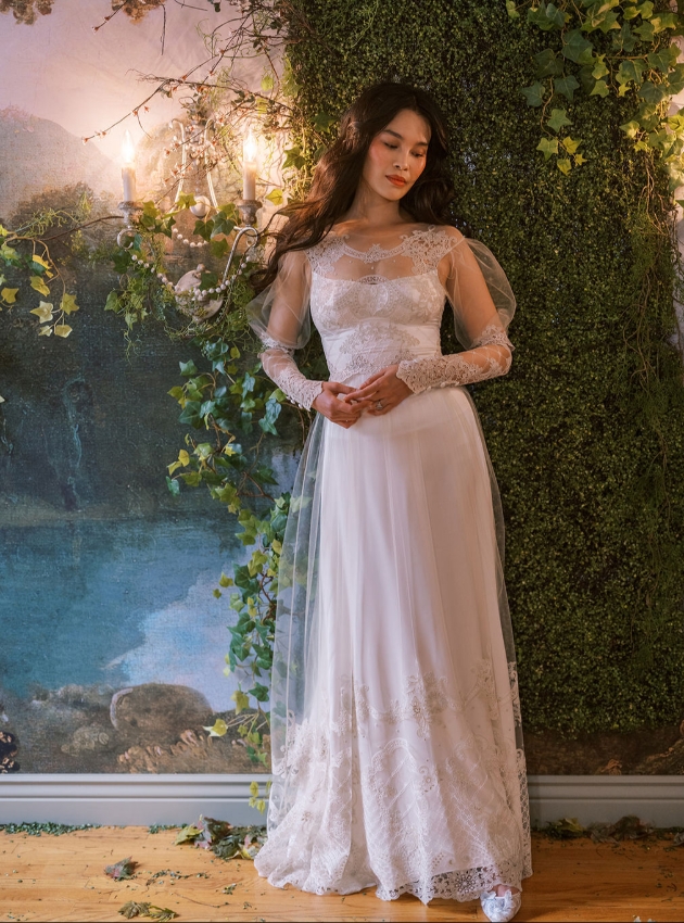 model in floor length wedding dress with sheer overlay on neck arms and skirt 