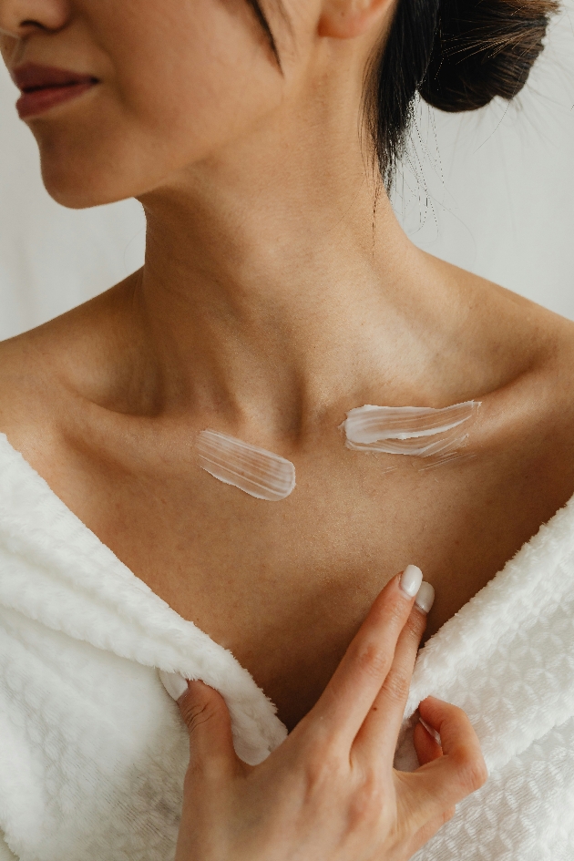 woman applying moisturiser to collarbone